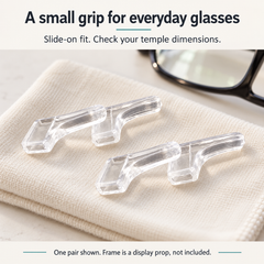 One pair of clear ear grips on a cloth beside an unbranded eyeglass frame prop